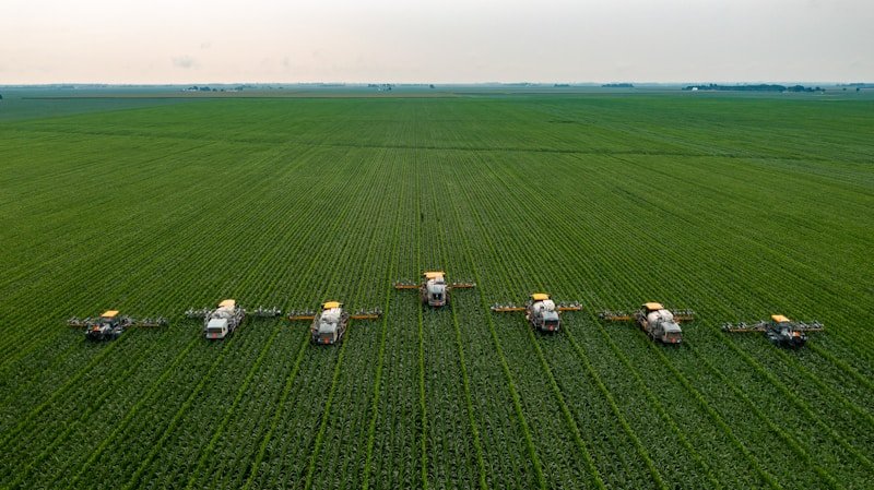 Flotte de pulvérisateurs agricoles modernes en action dans un grand champ